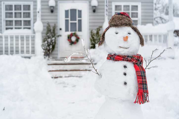 Snowman in front of home on winter day.