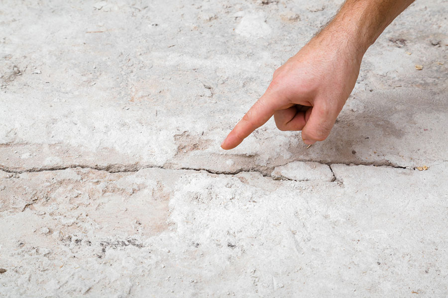 A hand points to a noticeable crack in a concrete floor, highlighting damage or wear—an issue that may require foundation crack repair in New Baltimore MI. A hand points to a noticeable crack in a concrete floor, highlighting damage or wear—an issue that may require foundation crack repair in New Baltimore MI.